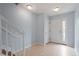Inviting foyer featuring light blue walls, tiled flooring, a staircase with white railings, and a front door at 110 Darley Dale Loop, Apex, NC 27502