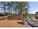 Wooden deck with green chairs and table, surrounded by lush trees and offering backyard views at 1104 Fanning Dr, Wake Forest, NC 27587