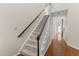 Carpeted staircase featuring a dark wood handrail and hardwood floors in the hallway at 1217 Hillingdon Way, Raleigh, NC 27614