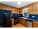 Functional kitchen with wood cabinets, black appliances, and blue tile backsplash at 12491 Buffalo Rd, Archer Lodge, NC 27527