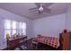 Cozy bedroom with natural light, hardwood floors, and ceiling fan above a colorful blanket at 1805 Shelton Ave, Durham, NC 27707