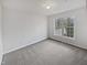 Bright bedroom features gray carpet, fresh paint, and a window showcasing the surrounding natural landscape at 20 Beechnut Ct, Franklinton, NC 27525