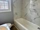 Bright bathroom featuring a white bathtub and marble-look tiled walls at 201 W Thorndale Dr, Oxford, NC 27565