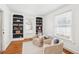 Sunlit living room featuring hardwood floors, built-in shelves, comfortable seating, and windows, creating a welcoming atmosphere at 202 W Lavender Ave, Durham, NC 27704