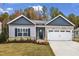 The home's facade has gray siding, a stone facade, a dark accent, and a two-car garage at 203 Jetson Creek Way, Youngsville, NC 27596