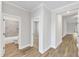 Bright hallway featuring wood-look flooring and white trim, leading to bathroom and bedrooms at 203 Jetson Creek Way, Youngsville, NC 27596