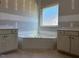 Bright bathroom featuring a corner tub, drywall, white vanities, and a large window at 28 Golden View Pl, Zebulon, NC 27597