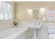 Well-lit bathroom with a pedestal sink, soaking tub, and window for natural light at 300 Mccauley St, Chapel Hill, NC 27516