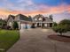 Elegant stone and brick home with a two-car garage, covered porch, and a circular driveway at sunset at 309 Shoreline Dr, Princeton, NC 27569