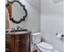Elegant powder room with dark wood vanity, decorative mirror, and neutral walls at 309 Shoreline Dr, Princeton, NC 27569