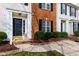 Inviting townhome entrance featuring a black front door, manicured landscaping, and a brick facade at 3122 Coxindale Dr, Raleigh, NC 27615