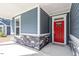 Inviting front porch featuring stone accents, a vibrant red door, and a covered entryway at 3424 Writt Ct, New Hill, NC 27562
