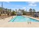 Community pool featuring a large, inviting swimming area with lounge chairs and a covered pavilion, surrounded by mature trees at 3424 Writt Ct, New Hill, NC 27562