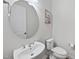 Half bathroom featuring a modern sink, toilet, decorative round mirror, and flower art at 616 Long Lake Dr, Fuquay Varina, NC 27526