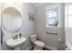 Stylish powder room featuring a round mirror, pedestal sink, and elegant fixtures at 76 Freewill Pl, Raleigh, NC 27603