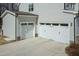 Attached two-car garage with white doors and stone accents at 76 Freewill Pl, Raleigh, NC 27603