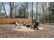Backyard with a gravel lounge area set up with rocking chairs around a firepit with mature trees and lawn at 810 Warwick Ct, Burlington, NC 27215