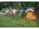 Charming exterior featuring beautiful landscaping, exterior lighting, and unique barn structures on a spacious lot at 8324 Humie Olive Rd, Apex, NC 27502