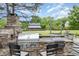 Built-in outdoor grill and cooking area with stone accents and seating, ideal for barbecues at 8324 Humie Olive Rd, Apex, NC 27502