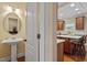 Well-lit powder room with pedestal sink and a glimpse into the kitchen area at 8912 Riverview Park Dr, Raleigh, NC 27613
