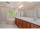 Bright bathroom with double vanity, a tub, a shower with glass door and a window at 8912 Riverview Park Dr, Raleigh, NC 27613