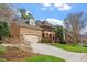 View of the home's exterior, showcasing stone and brick finishes, a spacious driveway, and manicured lawn at 8912 Riverview Park Dr, Raleigh, NC 27613