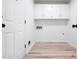 Clean and organized laundry room with white cabinets and wood-look flooring at 109 Hardee St, Clayton, NC 27520