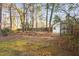 A spacious, wooded backyard featuring a storage shed and partial fencing at 1201 Deerfield Dr, Cary, NC 27511