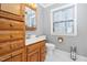 Bathroom with single sink vanity, oak cabinets, and a window with blinds at 1201 Deerfield Dr, Cary, NC 27511