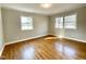 Bright bedroom featuring hardwood floors, two windows, and neutral paint at 128 Barclay Rd, Durham, NC 27712