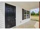 Close-up of a sleek black front door with white siding and dark-shuttered windows at 1286 W Blackman Rd, Dunn, NC 28334