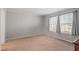 A light-filled, carpeted bedroom featuring two windows and neutral wall coloring at 129 Shawnee Dr, Louisburg, NC 27549