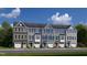 Charming row of townhouses with unique color schemes, attached garages, and neat landscaping under a blue sky at 1364 Chowan Ave, Durham, NC 27713