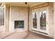 Covered patio with brick fireplace and double doors leading to the outdoor living space, offering a cozy retreat at 164 Arabella Ct, Cary, NC 27518
