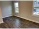 A sunlit bedroom showcasing wood flooring and two bright windows offering exterior views at 1913 Fishamble St, Fuquay Varina, NC 27526