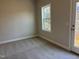 A well-lit bedroom with neutral carpet, a bright window, and a glass door to the outside at 1913 Fishamble St, Fuquay Varina, NC 27526