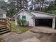 White detached garage with an open door, visible concrete flooring, and lush green surroundings at 229 Short St, Wendell, NC 27591