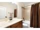 Bright bathroom with a granite countertop, dark wood cabinets, a tub with tile surround, and a shower curtain at 306 Village Orchard Rd, Cary, NC 27519