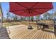 A spacious wooden deck with outdoor grill, red umbrella and railing that overlooks a large backyard at 33 Song Breeze Cir, Angier, NC 27501