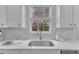 Kitchen sink under a window providing natural light, with white cabinetry and countertops at 413 Westfalen Dr, Cary, NC 27519