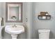 Cozy half bathroom with pedestal sink, toilet, mirror, and decorative shelf at 424 Crystal Spring Dr, Sanford, NC 27332