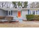 Close up of the front of a home with a striking orange door, gray siding and blue shutters at 4814 Fayetteville Rd, Durham, NC 27713