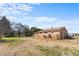 Backyard view showcasing a brick home exterior, grassy area, and a tree line, set against a bright blue sky at 492 Pixley Pritchard Rd, Timberlake, NC 27583