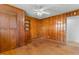 Spacious bedroom featuring wood paneling, ceiling fan, hardwood floors, and built-in shelving at 492 Pixley Pritchard Rd, Timberlake, NC 27583