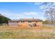 Exterior view of a brick home with a metal roof and fenced yard surrounded by a well-maintained lawn and mature trees at 492 Pixley Pritchard Rd, Timberlake, NC 27583