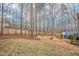 Spacious backyard featuring a wood fence, mature trees, and custom deck with blue stairs at 507 Town Crier Ct, Hillsborough, NC 27278