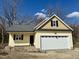 Charming home featuring a bright yellow exterior, stone accents, and an attached garage under a cloudy blue sky at 512 Hicksmill Rd, Oxford, NC 27565