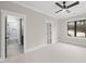 Bedroom with neutral walls, a black ceiling fan, a trimmed window, and view into a bathroom at 5213 Bent Leaf Dr, Raleigh, NC 27606