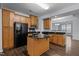 Spacious kitchen featuring wood cabinetry, black appliances, granite countertops and island, and open layout at 533 Berry Chase Way, Cary, NC 27519