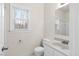 Well-lit bathroom featuring a toilet, sink, and framed mirror, with a view of the yard through the window at 5738 Sentinel Dr, Raleigh, NC 27609